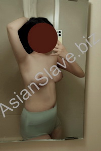 A BDSM girl is taking a picture of herself in the mirror.